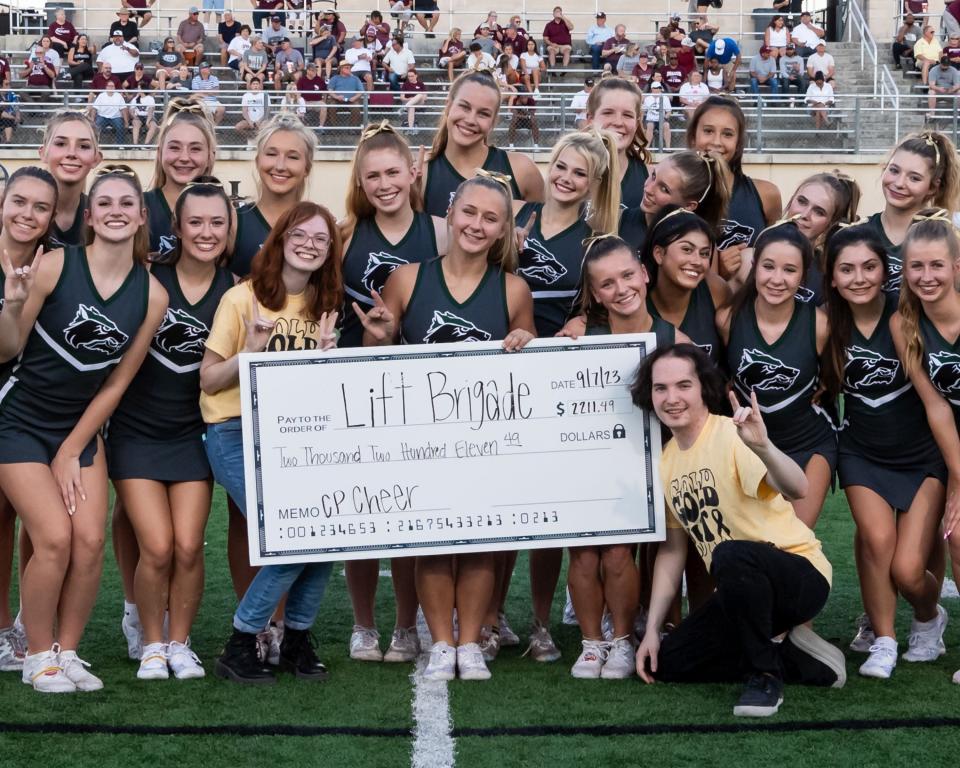 Cedar Park cheerleaders present their donation to Lift Brigade, a childhood cancer support organization, founded by Lance White (kneeling) during his own cancer treatment, using his Make-A-Wish opportunity. It was "Gold Out" night for Cedar Park football, supporting childhood cancer victims.