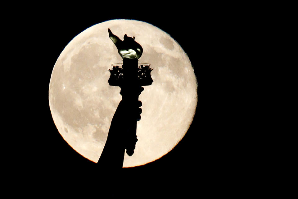 FILE - In this July 31, 2015, file photo, a blue moon rises behind the torch of the Statue of Liberty seen from Liberty State Park in Jersey City, N.J. A blue moon happens when the moon rises in its full stage twice during the same month. (AP Photo/Julio Cortez, File)