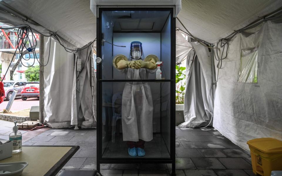 A health worker stands inside a non-contact chamber called the "CoV SHIELD" before taking swab samples to test for COVID-19