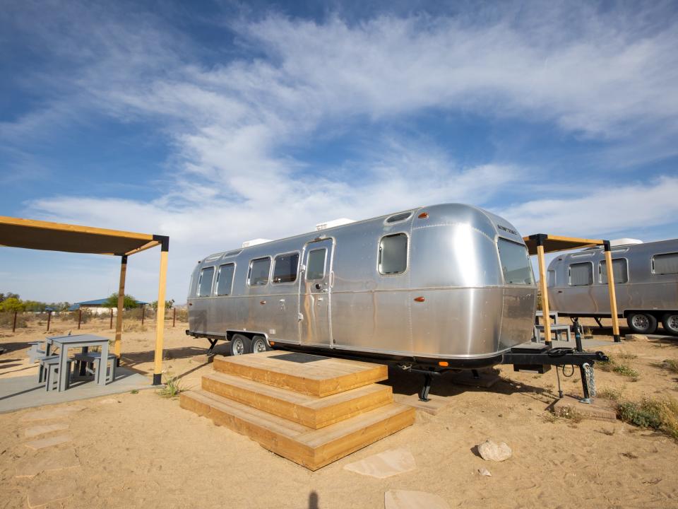 Airstream trailers outside at Autocamp's Joshua Tree location. There's tables and chairs between each trailer.