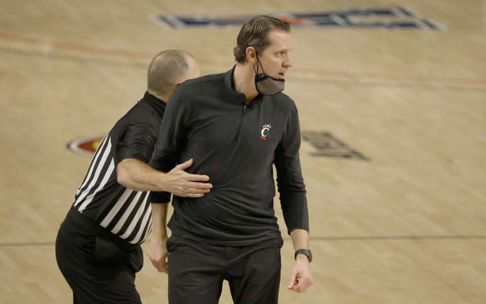 Cincinnati head coach John Brannen is pulled back toward the team bench by a game official as Cincinnati plays Wichita State during the second half of an NCAA college basketball game in the semifinal round of the American Athletic Conference men's tournament Saturday, March 13, 2021, in Fort Worth, Texas. (AP Photo/Ron Jenkins)