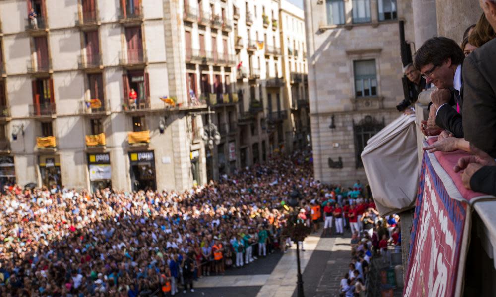 Carles Puigdemont looks down from the balcony of city hall in Barcelona