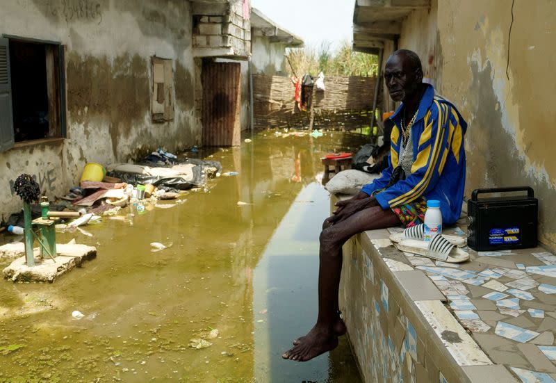 Mr. Issa Camara, a resident, sits in the flooded alley of his home after heavy rains in Yeumbeul district on the outskirts of Dakar