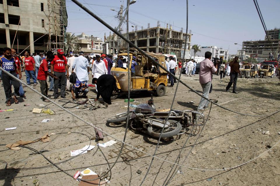 Pakistani officials collect evidence at the site of an explosion in Karachi, Pakistan, Friday, April 25, 2014. A powerful bomb exploded Friday in an upscale residential area of southern Pakistan, killing several people and wounding others, authorities said. The attack took place in the neighborhood of Clifton in Karachi, the capital of southern Sindh province, senior police officer Abdul Khaliq Sheikh said. The bomb badly damaged several vehicles and a nearby multi-story building. (AP Photo/Fareed Khan)