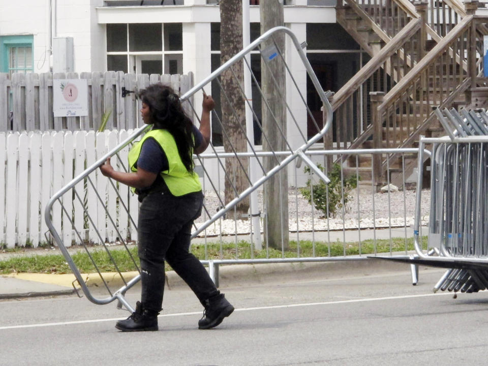 A worker places a section of metal barricade along a main road on Tybee Island, Ga., on Tuesday, April 16, 2024, a few days ahead of the weekend beach party known as Orange Crush. Black college students started the spring bash at Georgia's largest public beach more than 30 years ago. Tybee Island officials are blocking roads and parking spaces and brining in about 100 extra police officers for the party this weekend, saying record crowds last year proved unruly and dangerous. (AP Photo/Russ Bynum)