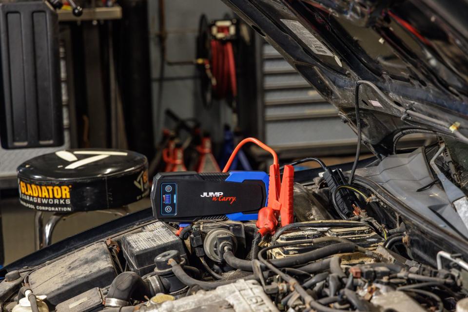 portable jump starter hooked onto car in garage