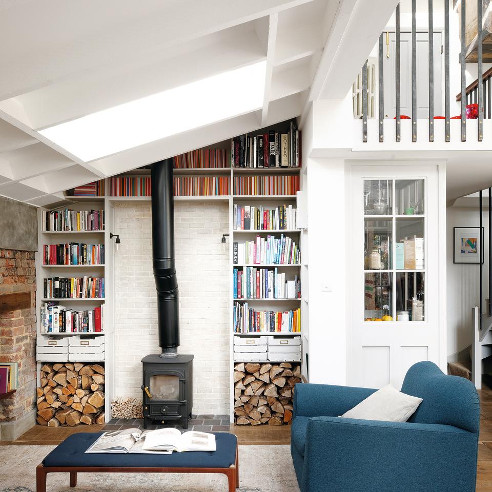 Living room with white walls, wood burner and built-in bookshelves.