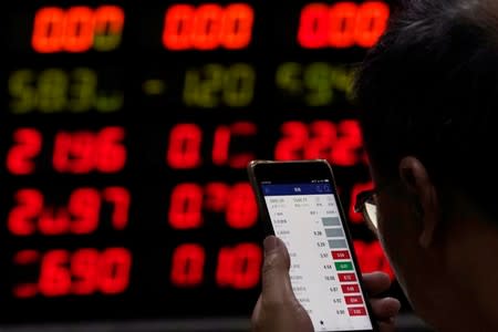 An investor checks stock information on a mobile phone at a brokerage house in Shanghai