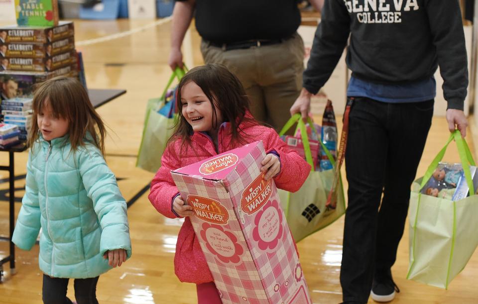 Samantha Winkle, 6, right, of Beaver Falls, smiles as she finishes up picking out toys with her sister, Gabriella Winkle, 4, at the Christian Assembly CARE Outreach Ministry 25th Annual Christmas Day dinner at Beaver Falls High School.