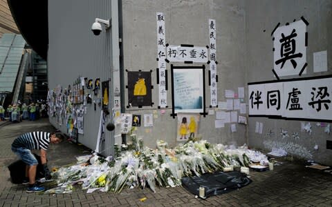 A woman cleans up a makeshift memorial near government headquarters in Hong Kong, Tuesday, July 2, 2019 - Credit: AP