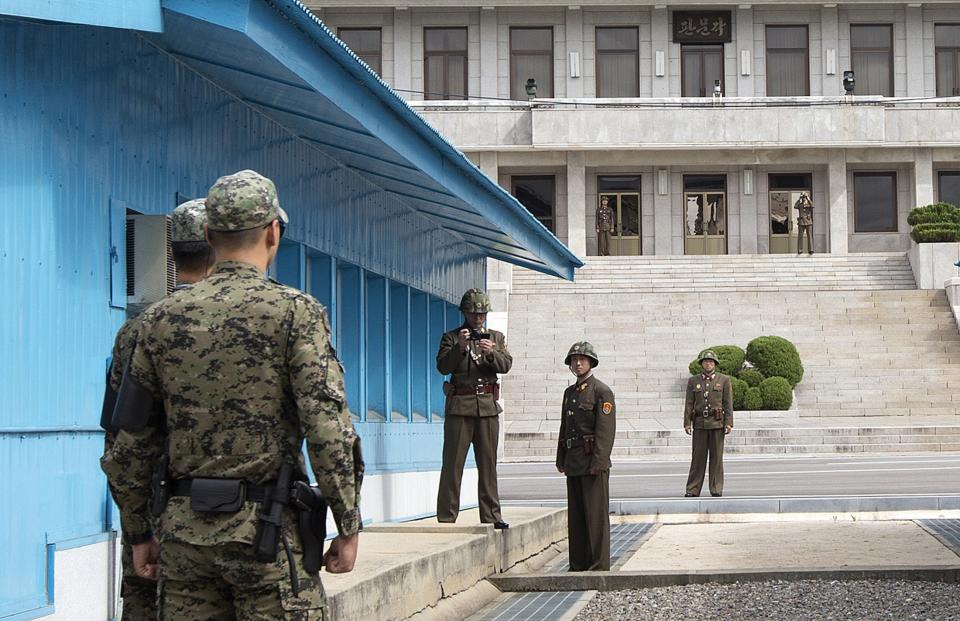 North Korean soldiers stand on the North Korean side, with one using a camera, as South Korean soldiers face them at the U.N. truce village building that sits on the border of the Demilitarized Zone (DMZ), the military border separating the two Koreas, during the visit of U.S. Secretary of Defense Chuck Hagel, in Panmunjom, South Korea September 30, 2013. Hagel toured the Korean DMZ on Monday, at times under the watchful eye of North Korean soldiers, and said the Pentagon had no plan to reduce its 28,500-member force in the South despite budget constraints. REUTERS/Jacquelyn Martin/Pool (SOUTH KOREA - Tags: POLITICS MILITARY)