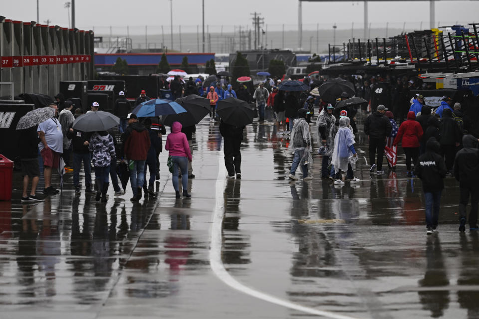 Race fans walk through the garage area while rain causes a delay to a NASCAR Cup Series auto race at Charlotte Motor Speedway Sunday, May 28, 2023, in Concord, N.C. (AP Photo/Matt Kelley)