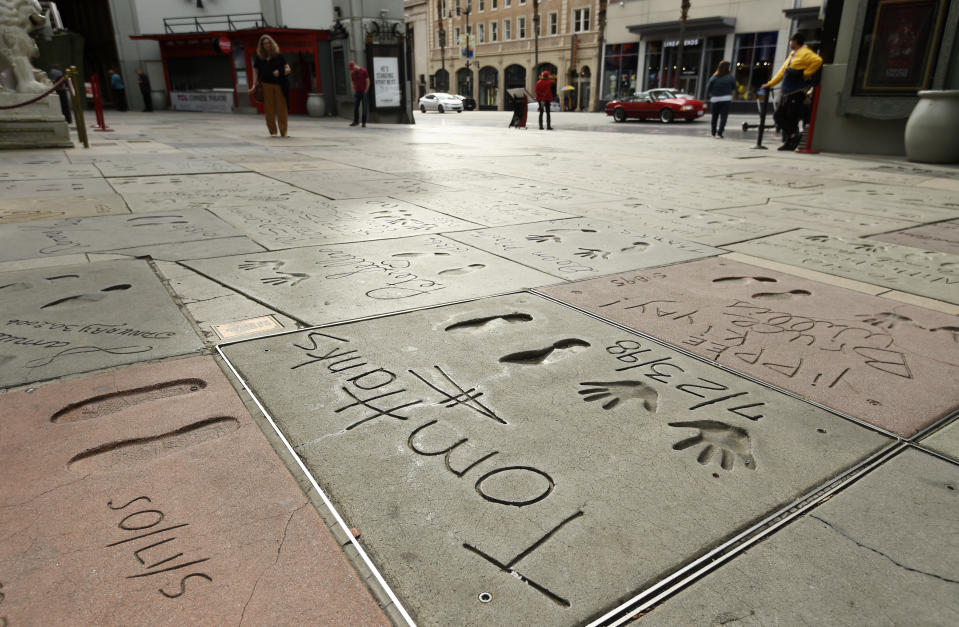 The cement inscription of actor Tom Hanks sits in the nearly empty forecourt of the TCL Chinese Theatre, Thursday, March 12, 2020, in the Hollywood section of Los Angeles. Hanks and his wife, actress-singer Rita Wilson, have tested positive for the coronavirus, the actor said in a statement Wednesday. For most people, the new coronavirus causes only mild or moderate symptoms. For some it can cause more severe illness. (AP Photo/Chris Pizzello)