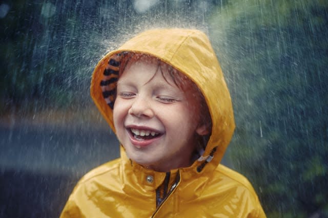 Happy smiling little boy in the rain