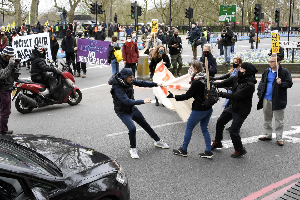 A man tries to rip a banner held by demonstrators blocking traffic during a 'Kill the Bill' protest in London, Saturday, April 3, 2021. The banner read Protect The Right To Protest. The demonstration is against the contentious Police, Crime, Sentencing and Courts Bill, which is currently going through Parliament and would give police stronger powers to restrict protests. (AP Photo/Alberto Pezzali)