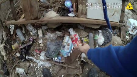 A still image captured from police body camera video appears to show a Baltimore police officer placing a small plastic bag in a trash-strewn yard as two colleagues look on (not shown) according to the Maryland Office of the Public Defender in this image released in Baltimore, Maryland, U.S. on July 19, 2017. Courtesy Baltimore Police Department/Handout via REUTERS