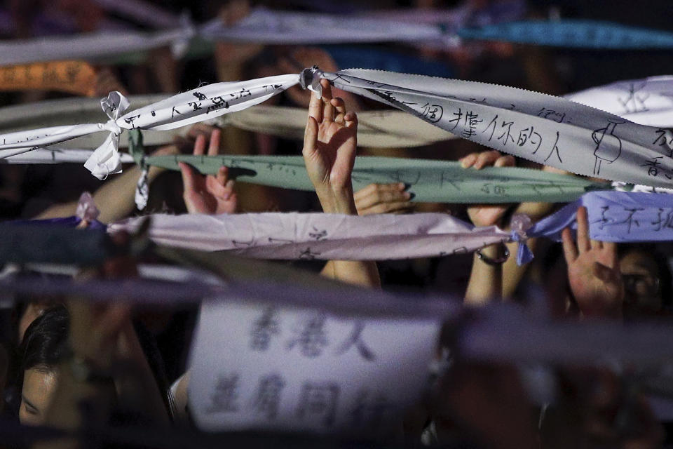 Attendees hold up tied message written banners together with a paper reads "Hong Kong people walk side by side" during a rally by mothers in Hong Kong on Friday, July 5, 2019. Student unions from two Hong Kong universities said Friday that they have turned down invitations from city leader Carrie Lam for talks about the recent unrest over her proposal to allow the extradition of suspects to mainland China. (AP Photo/Andy Wong)