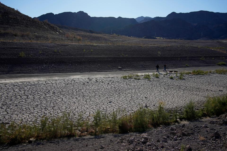 People walk by cracked earth in an area once under the water of Lake Mead at the Lake Mead National Recreation Area, Jan. 27, 2023, near Boulder City, Nevada.