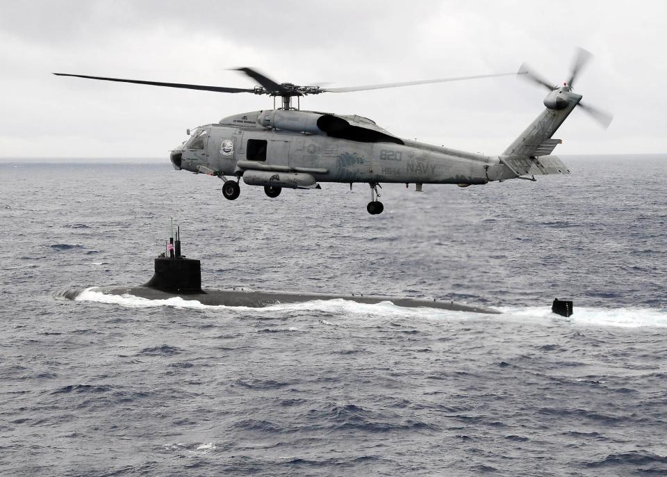 An HH-60H Sea Hawk helicopter from the Chargers of Helicopter Anti-Submarine Squadron 14 flies over the Seawolf-class attack submarine USS Connecticut.