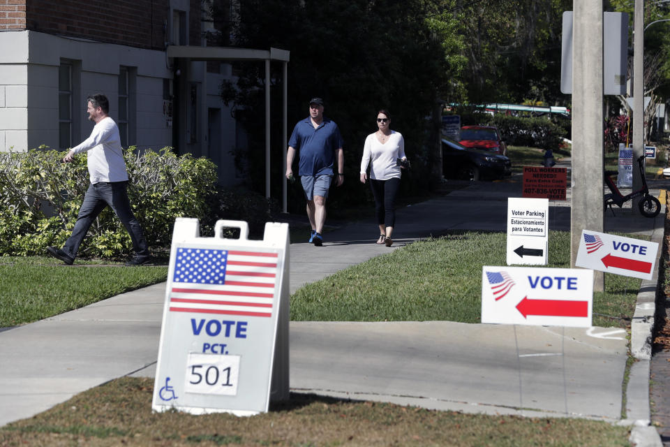 FILE - In this March 17, 2020 file photo, voters head to a polling station to vote in Florida's primary election in Orlando, Fla. Florida felons must pay all fines, restitution and legal fees before they can regain their right to vote, a federal appellate court ruled Friday, Sept, 11. Reversing a lower court judge's decision that gave Florida felons the right to vote regardless of outstanding legal obligations, the order from the U.S. 11th Circuit Court of Appeals was a disappointment to voting rights activists and could have national implications in November’s presidential election. (AP Photo/John Raoux, File)