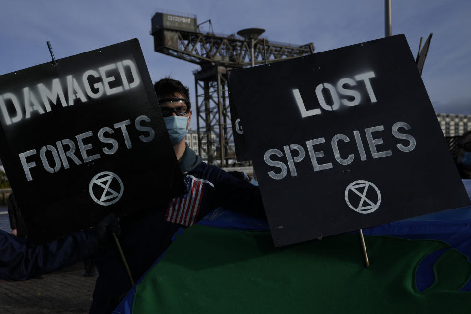 A demonstrator from Extinction Rebellion holds placards at a protest about Loss and Damage to the earth during the COP26 Climate Change conference in Glasgow, Scotland, Sunday, Nov. 7, 2021. (AP Photo/Alastair Grant)