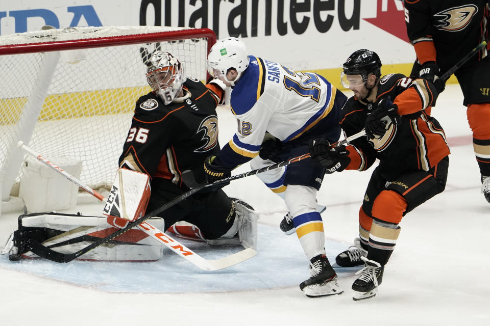 St. Louis Blues' Zach Michael Sanford, center, gets his shot stopped by Anaheim Ducks goaltender John Gibson while defended by Ducks' Kevin Shattenkirk, right, during the first period of an NHL hockey game Saturday, Jan. 30, 2021, in Anaheim, Calif. (AP Photo/Jae C. Hong)