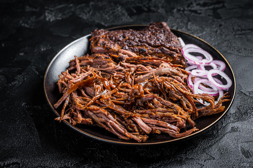 A plate of shredded barbecued meat served with slices of raw onion on the side