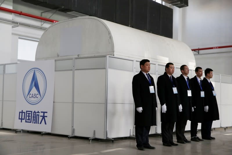 Security personnel stand next a logo of CNSA before a hovering-and-obstacle avoidance test for China's Mars mission in Huailai