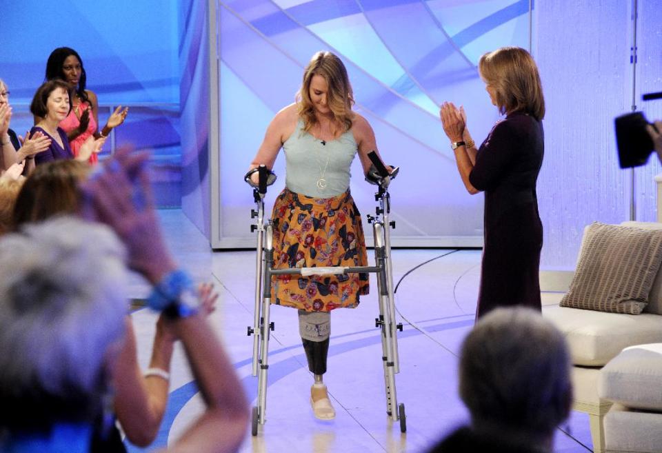 This image released by Disney-ABC Domestic Television shows host Katie Couric, right, applauding as Aimee Copeland, 24, of Snellville, Ga., who survived a rare fleshing-eating disease, as she arrives for an exclusive interview on the new daytime talk show "Katie," Tuesday, Sept. 11, 2012, in New York. Copeland walked to the stage using a new walker. Copeland was joined in New York by her parents and sister. After Couric interviewed the family, she announced that an Atlanta-area Chevrolet dealer was in the studio to give Copeland a new minivan that will be retrofitted so she can drive it. Copeland got the infection in May after falling from a zip line and gashing her leg. Doctors had to amputate both hands, her left leg and right foot. She returned home to suburban Atlanta last week after three months in the hospital and a rehabilitation clinic. (AP Photo/Disney-ABC Domestic Television, Ida Mae Astute)