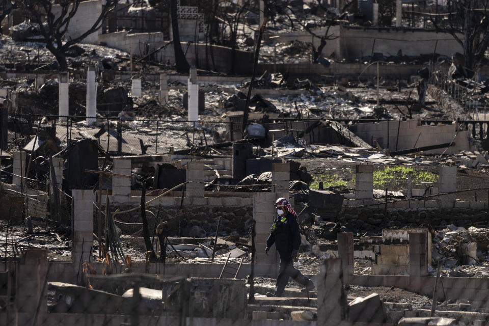 FEMA's search and rescue team member works in a residential area consumed by a wildfire in Lahaina, Hawaii, Friday, Aug. 18, 2023. An emergency official who defended a decision to not sound outdoor alert sirens on Maui as a ferocious fire raged has resigned. (AP Photo/Jae C. Hong)