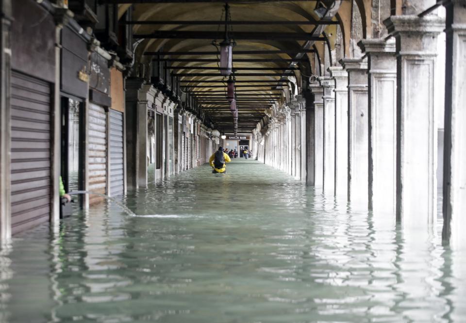 People wade their way through water in Venice, Italy, Friday, Nov. 15, 2019. Waters are rising in Venice where the tide is reaching exceptional levels just three days after the Italian lagoon city experienced its worst flooding in more than 50 years. (AP Photo/Luca Bruno)