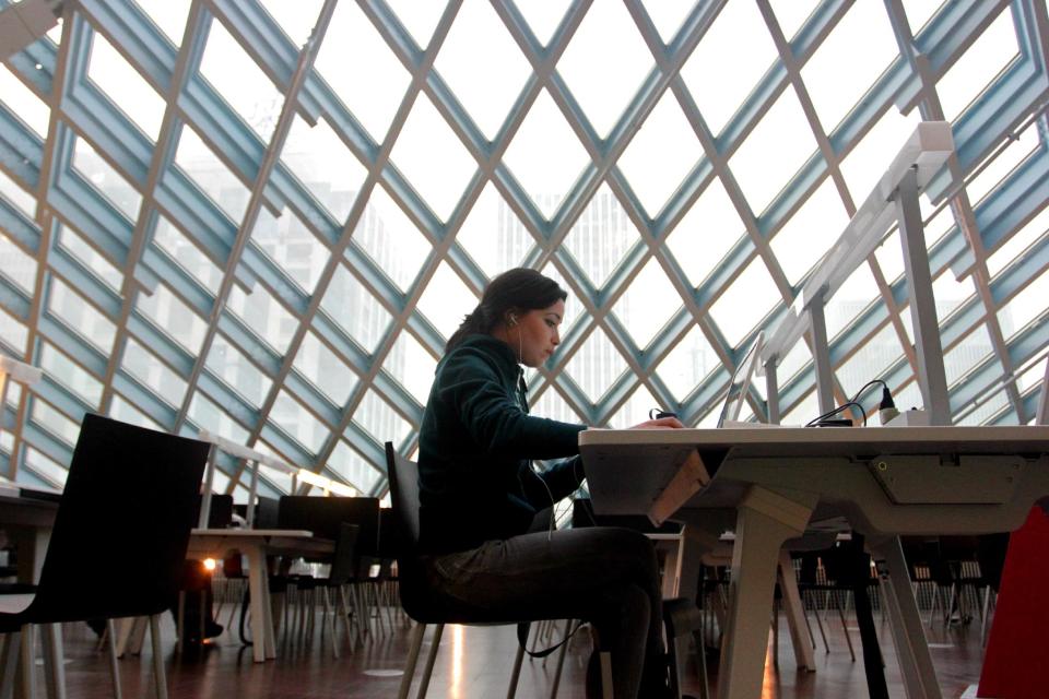 This image taken April 3, 2013 shows a woman working on her laptop at the Seattle Central Library in downtown Seattle. The $165 million building’s unusual design and decoration attracts visitors from all over the world. (AP Photo/Manuel Valdes)