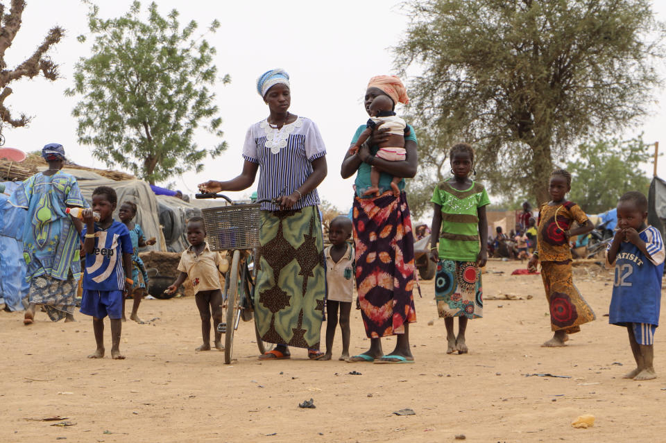 Women and children walk in a makeshift site for displaced people in Kongoussi, Burkina Faso Thursday, June 4, 2020. Jihadist violence has dramatically escalated in Burkina Faso in recent years. The country's military has struggled to contain the violence. (AP Photo/Sam Mednick)