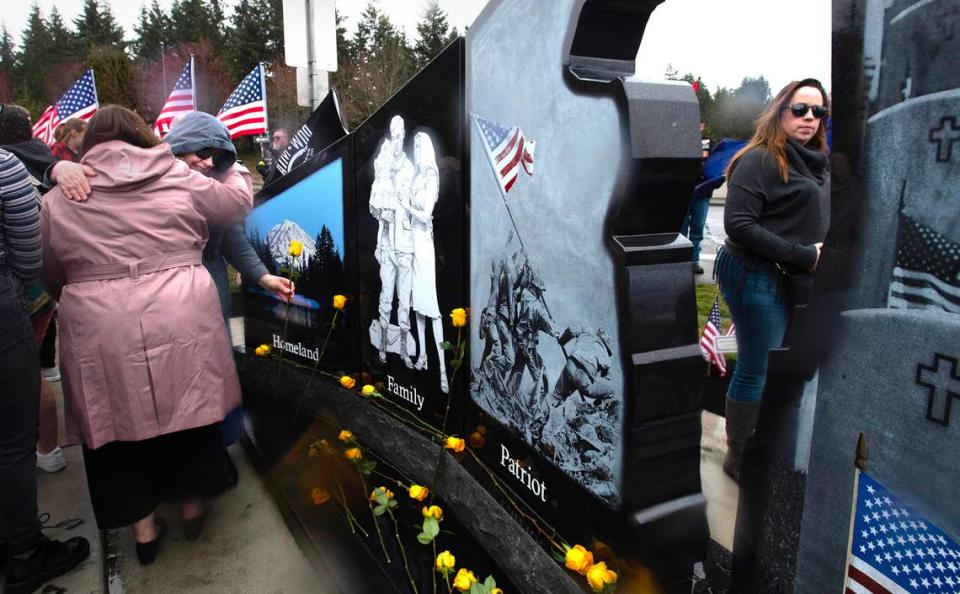 Jennifer Parmar of Rainier receives a hug as she places a yellow rose to honor her late husband, Iraq War Army veteran Sfc. Abraham Parmer, during the dedication and unveiling of the new Gold Star Families Memorial Monument at the Lacey Civic Plaza on Friday, March 31.