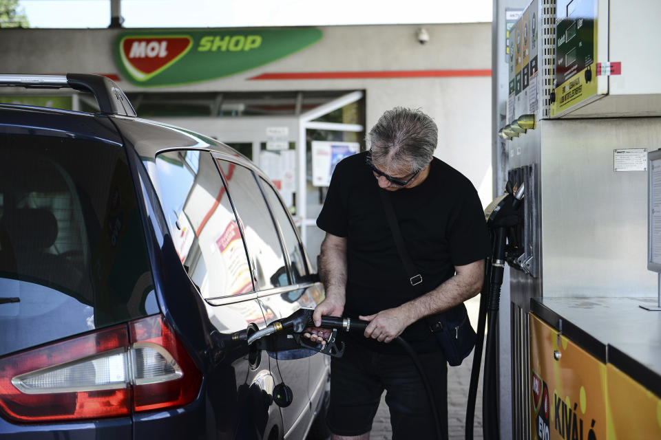 A man fills up his car at a petrol station in Budapest, Hungary, Sunday, June 12, 2022. Hungary has placed price caps on fuel and some food and imposed special taxes on industries as the government tries to ease an economic downturn and the highest inflation in nearly 25 years. (AP Photo/Anna Szilagyi)