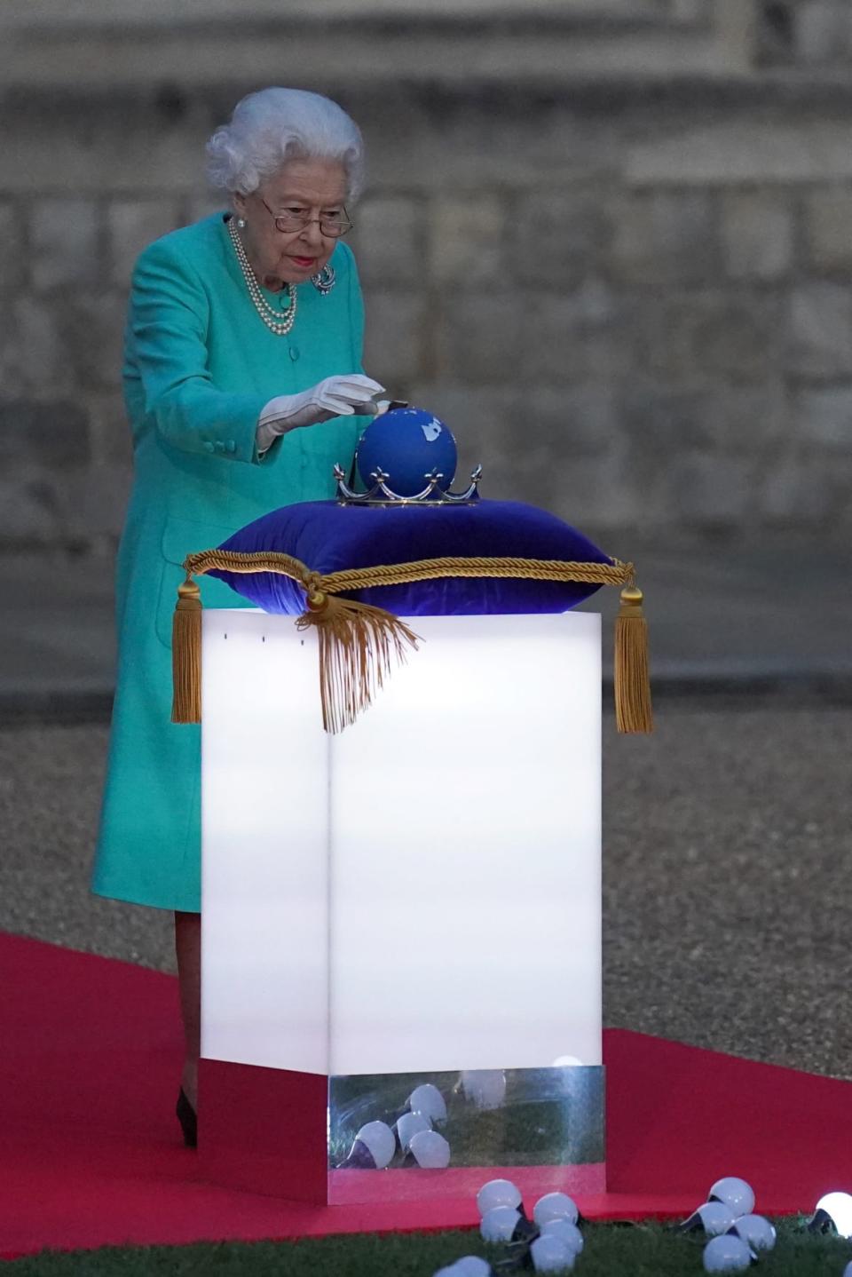 <div class="inline-image__caption"><p>Queen Elizabeth II touches the Commonwealth Nations Globe to start the lighting of the Principal Beacon outside of Buckingham Palace.</p></div> <div class="inline-image__credit">Steve Parsons/Getty</div>