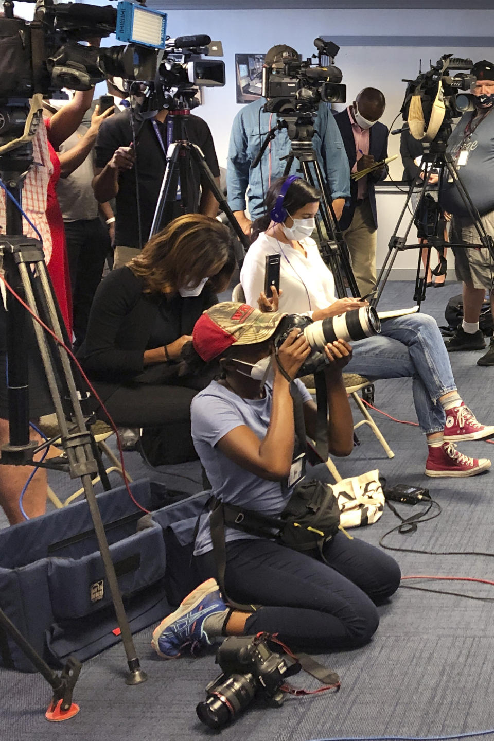 Atlanta Journal-Constitution staff photojournalist Alyssa Pointer, kneeling, works during a news conference, Tuesday, June 2, 2020, in Atlanta. Pointer was detained by officers of the Georgia Department of Natural Resources during a protest in downtown. Pointer said her press badge was clearly displayed, and she identified herself to law enforcement. (AP Photo/Kate Brumback)