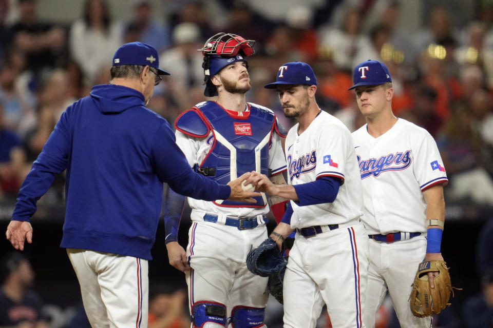 Texas Rangers starting pitcher Andrew Heaney, center right, hands the ball to manager Bruce Bochy, left, after being pulled during the first inning in Game 4 of the baseball American League Championship Series against the Houston Astros Thursday, Oct. 19, 2023, in Arlington, Texas. (AP Photo/Godofredo A. Våsquez)