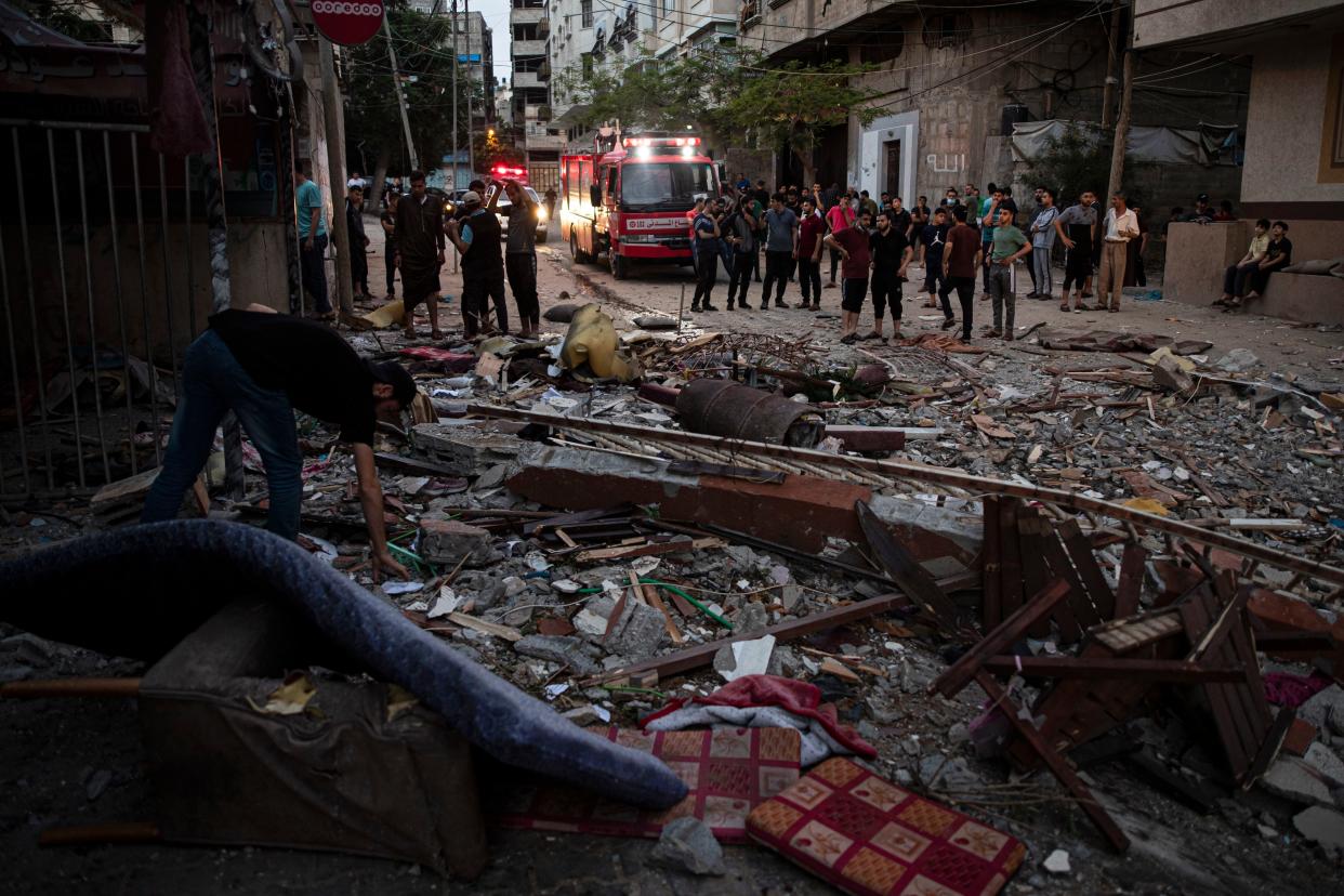 A Palestinian man inspects the rubble of a partially destroyed residential building after it was hit by Israeli missile strikes at the Shati refugee camp in Gaza City, early Tuesday, May. 11, 2021.