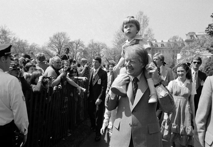 President  Jimmy  Carter holds his grandson, Jason Carter, 2, on his shoulders while visiting the South Lawn on April 11, 1977, site of the Easter Egg Roll at the White House in Washington. 