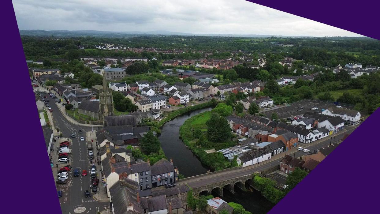 An aerial view of Antrim in which trees, houses and a church are visible along the banks of a river