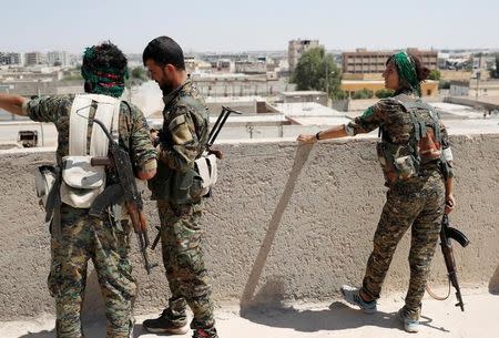 Sheen Ibrahim, Kurdish fighter from the People's Protection Units (YPG) stand on a roof top together with other YPG fighters in Raqqa, Syria June 16, 2017. REUTERS/Goran Tomasevic