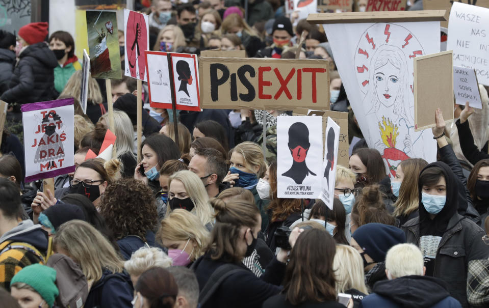 Women's rights activists hold placards during a protest in Warsaw, Poland, Wednesday, Oct. 28, 2020 against recent tightening of Poland's restrictive abortion law. Massive nationwide protests have been held ever since a top court ruled Thursday that abortions due to fetal congenital defects are unconstitutional.(AP Photo/Czarek Sokolowski)