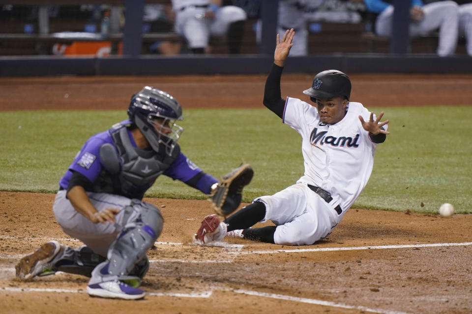 Miami Marlins' Jose Devers slides into home plate to score as Colorado Rockies catcher Elias Diaz waits for the throw during the fifth inning of a baseball game Thursday, June 10, 2021, in Miami. (AP Photo/Wilfredo Lee)