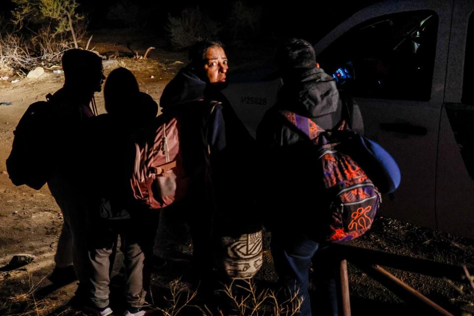 A migrant family from Colombia huddles in the darkness.