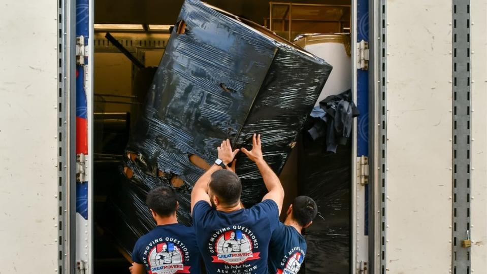 Three staff members for Great Movers NYC carefully load a moving truck.
