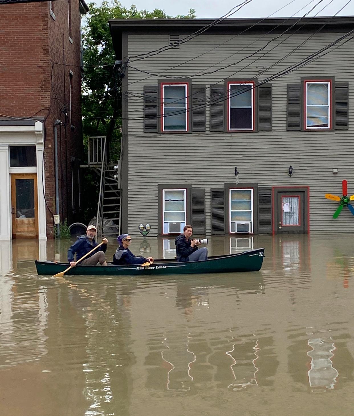 Three people in a canoe paddle through floodwaters along Elm Street in Montpelier, Vermont on Tuesday (AP)