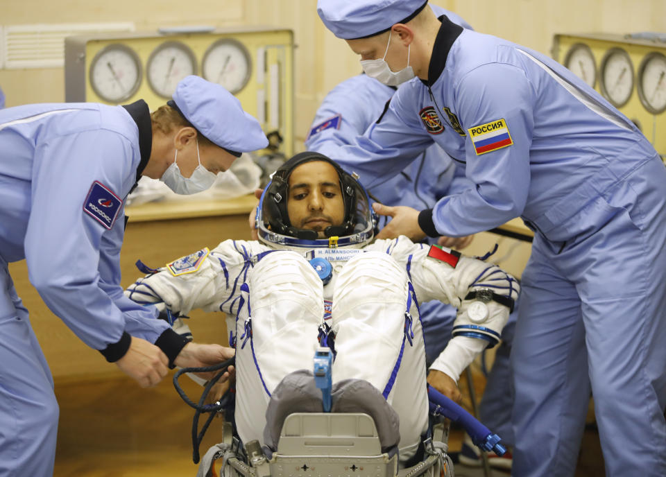 Russian Space Agency experts help United Arab Emirates astronaut Hazza Almansoori, member of the main crew of the expedition to the International Space Station (ISS), to sit during inspecting his space suit prior the launch of Soyuz MS-15 space ship at the Russian leased Baikonur cosmodrome, Kazakhstan, Wednesday, Sept. 25, 2019. (AP Photo/Dmitri Lovetsky)
