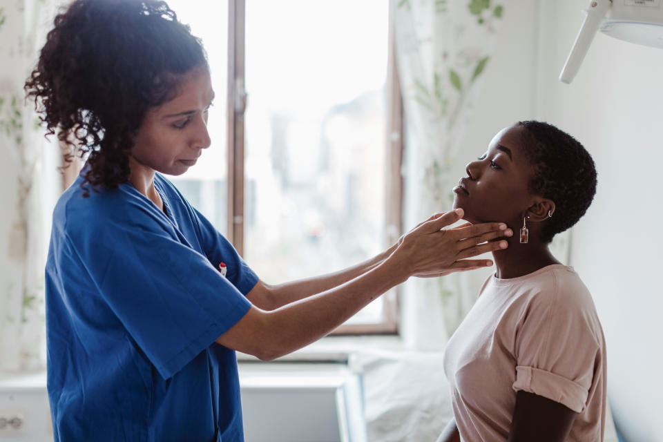 Female nurse examining throat of young patient in hospital