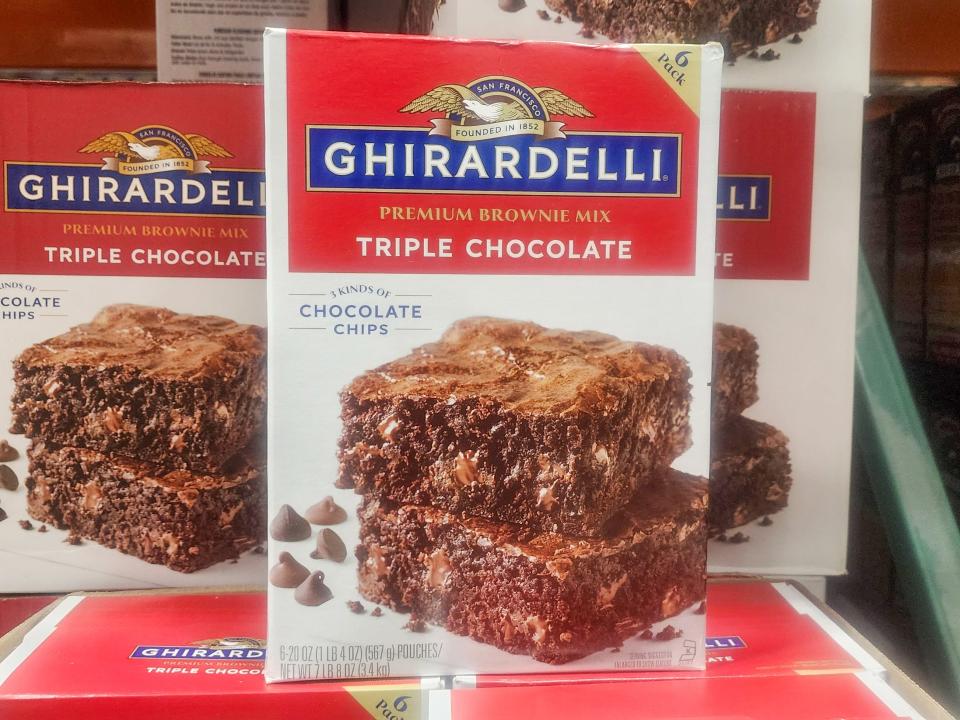 Three white boxes with Ghirardelli label and pictures of brownies with chocolate chips on the front. The box has red labels